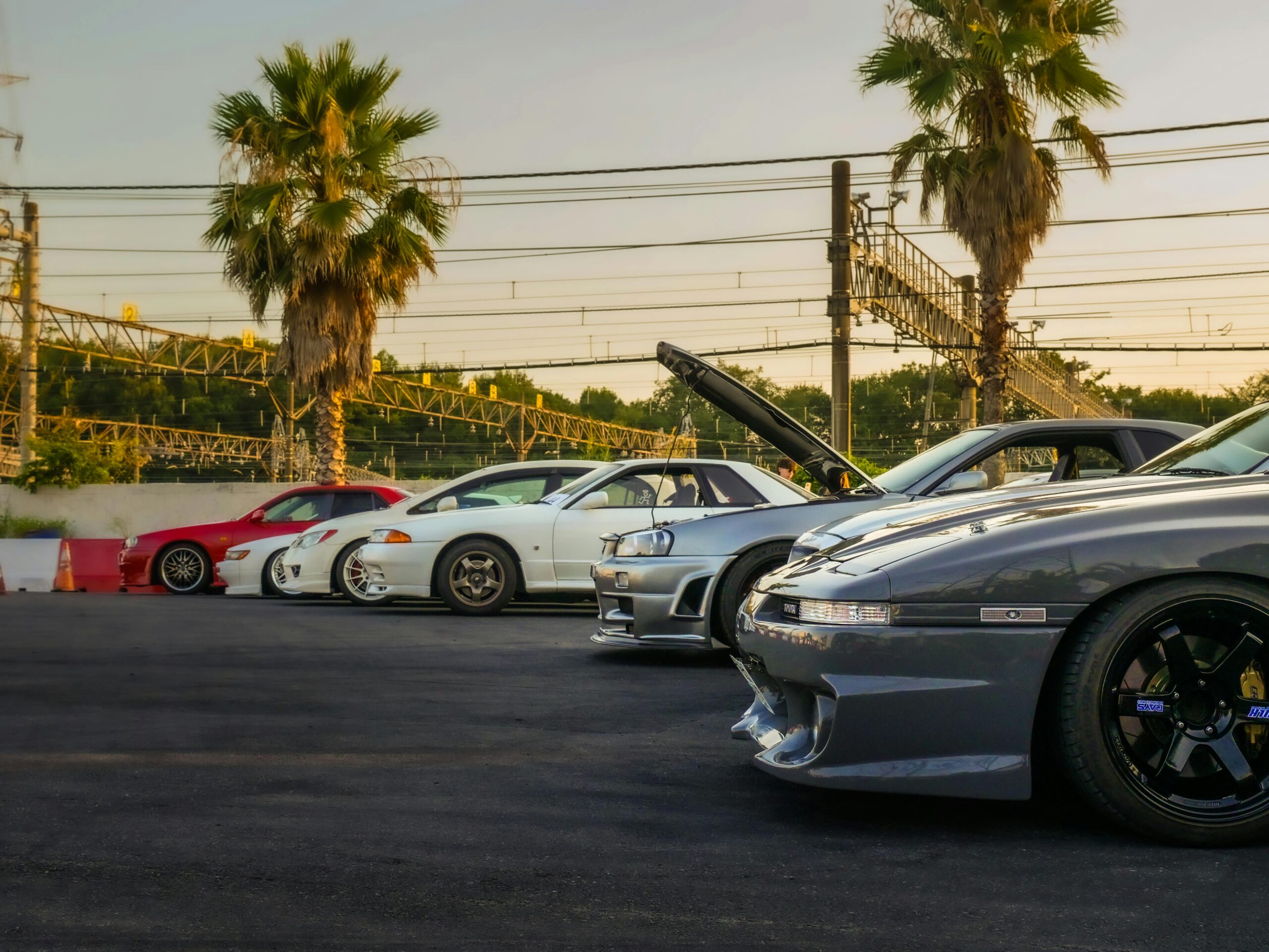 Lineup of classic JDM cars at a car meet in Tokyo, Japan, featuring Nissan and Toyota models.